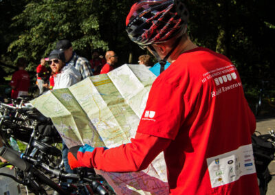 Uczestnik rajdu w czerwonej koszulce patzry na rozłożoną mapę.