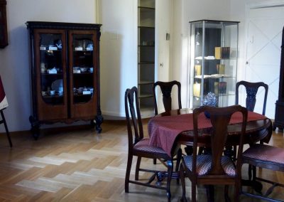 Na srodku stół i drewniane krzesła. Z lewej plakat z wystawy Chwała rodu Henckel von Donnersmarck, żeliwny sejf i gablota z eksponatami.