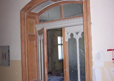 Uczylone, obdrapane drzwi, za którymi widać zniszczone ściany.