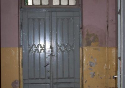 Zniszcone drzwi boczne do pałacu od wewnatrz. Wkoło drzwi obrdapane ściany.