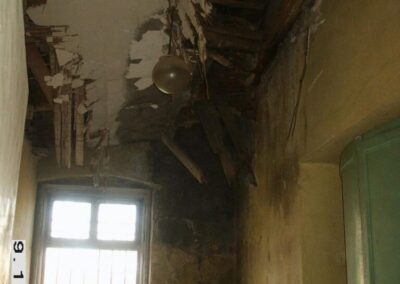 Sypiący się sufit i zniszczone sciany w pomieszczeniu.