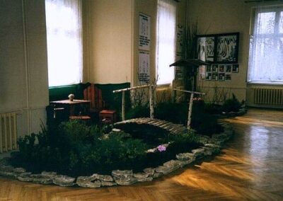 Rośliny i mostek z drewna otoczone kamieniami - ułożone w sali balowej.