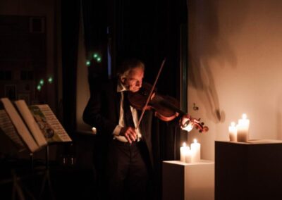 Ulrich von Wrochem grający na altówce. W sali jest ciemno, światło dochodzi z zapalonych świeczek stojących przy ścianie po prawej stronie. Z lewej strony stoi ustawiony pulpit z nutami.