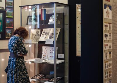 Kobieta w sukience przygląda się wystawie w gablocie. Po prawej stronie fragment planszy z wystawy o Donnersmarckach.