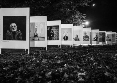 Czarno-biale zdjęcia znanych osób na planszach ustawione w parku.