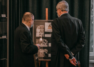 Hrabia i dr Kuzio-Podrucki stojący przed planszą z fotografiami na sztaludze.