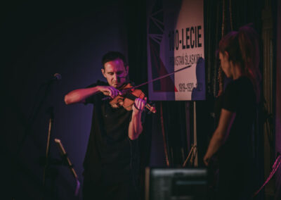 Mateusz Mos gra na skrzypcach, obok stoi Kasia Moś