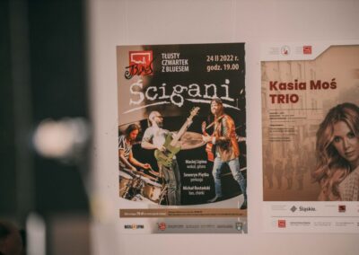 Plakat Tłusty czwartek z bluesem Ścigani wiszący obok plakatu z koncerty Kasia Moś Trio.