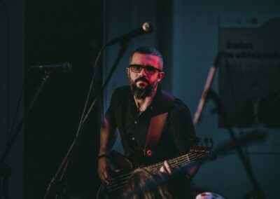 Michał Rostański grający na gitarze basowej. Za nim napis Blues.