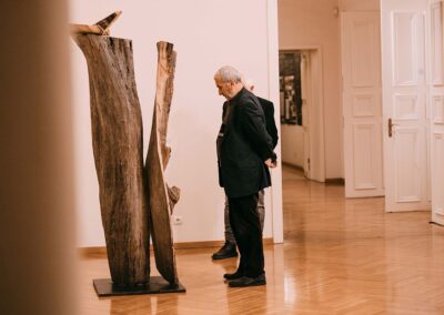 Dwóch mężczyzn przygląda się długiej i wysokiej rzeźbie z drewna.