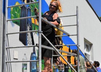 Beata Hetmańczyk, komisarz pleneru, na rusztowaniu podczas malowania muralu.