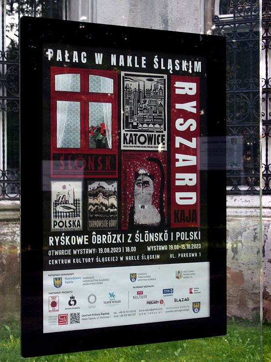 Szklana gablota przed pałacem, w której wisi plakat z wystawy Ryszarda Kai.