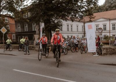 Komandorzy rajdu na czele grupy rowerzystów wyjeżdżaja z placu przed budynkiem ZSAP.