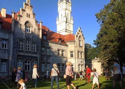 Grupa ludzi tańczących przed pałacem w Nakle Śląskim.