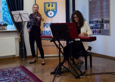 Julia Loska grająca na skrzypcach, obok niej pianistka Izabela Wilga grająca na insttrumencie klawiszowym.