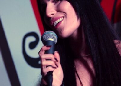 Adrianna Noszczyk - długowłosa brunetka, śpiewa do mikrofonu.