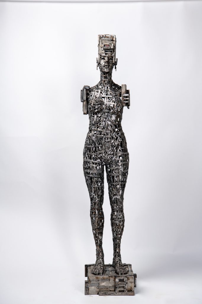 Rzeźba z metalu i mechanizmów zegara przedstawiająca postać ludzką.
